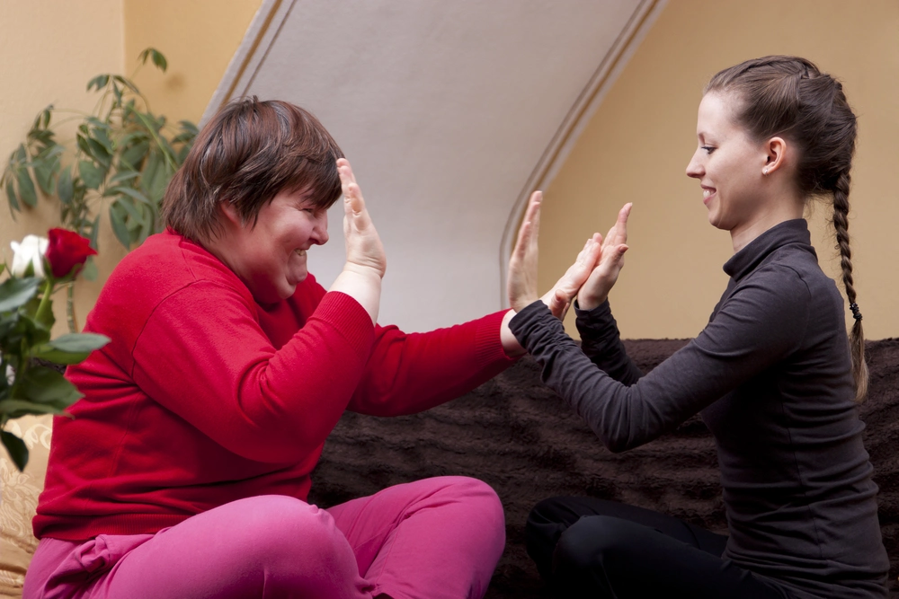 Carer playing with down syndrome disabled women