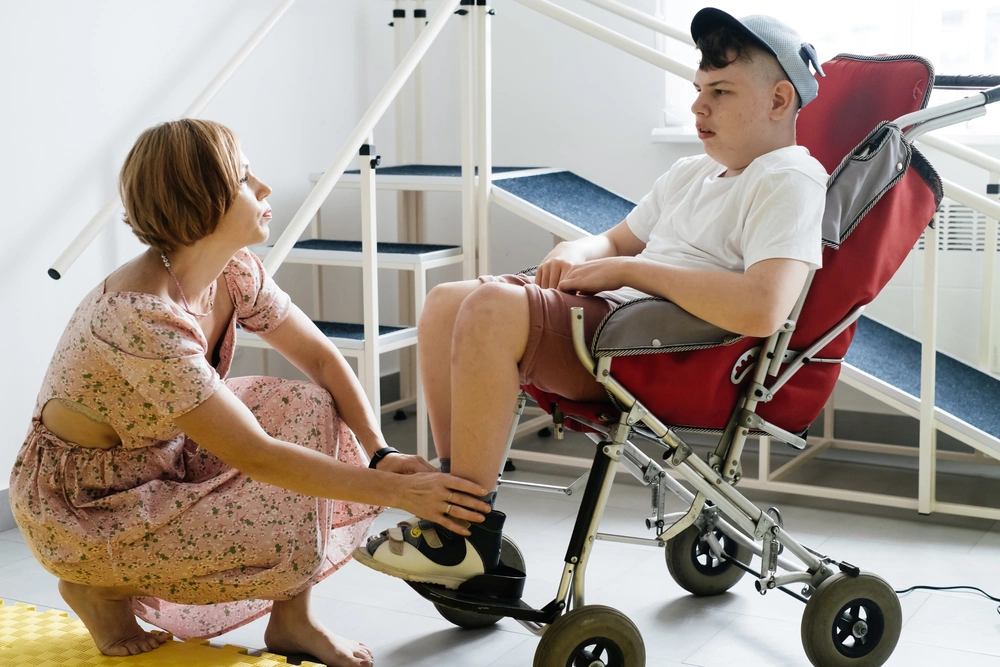 Disabled young boy on wheelchair with caretaker