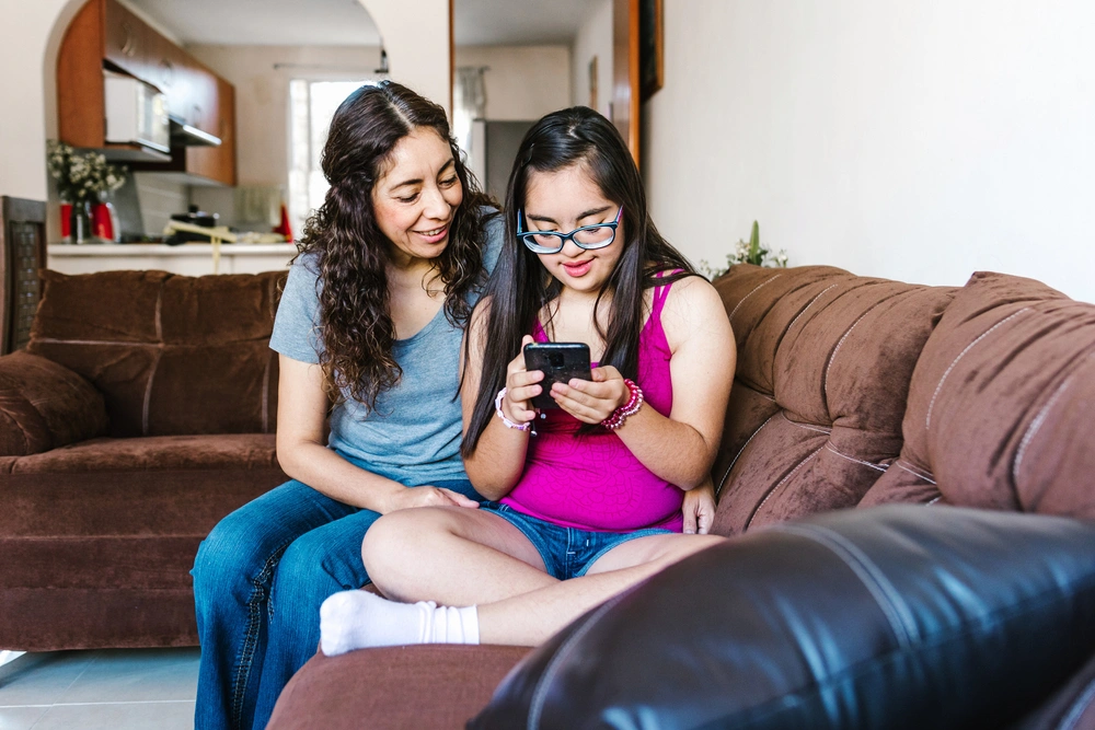 Disabled young girl with nurse, sitting on sofa
