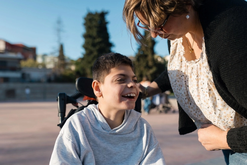 Disabled young boy on wheelchair with caretaker